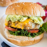 An air fryer chicken burger stacked with all the fixings on a white plate.