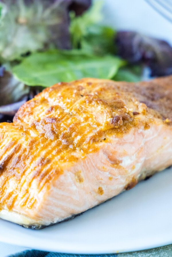 Close up of a salmon fillet on a plate with a salad.