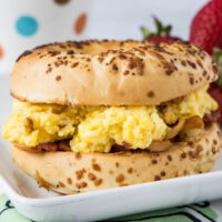 An egg and bacon bagel sandwich on a plate