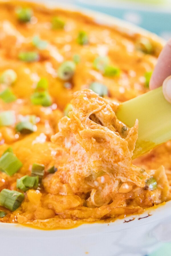 close up dipping celery into buffalo chicken dip