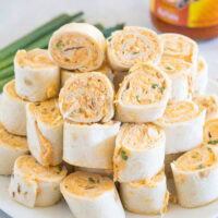 Buffalo chicken pinwheels stacked on a white plate.