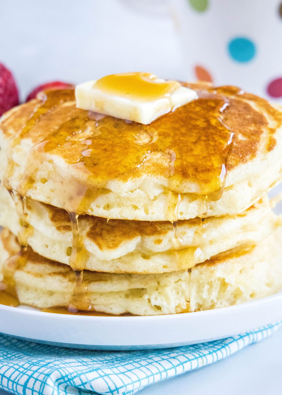 These easy diner-style buttermilk pancakes are thick, fluffy, perfectly sweet, and have just a hint of tanginess from the buttermilk. Close up of a stack of pancakes topped with butter and syrup