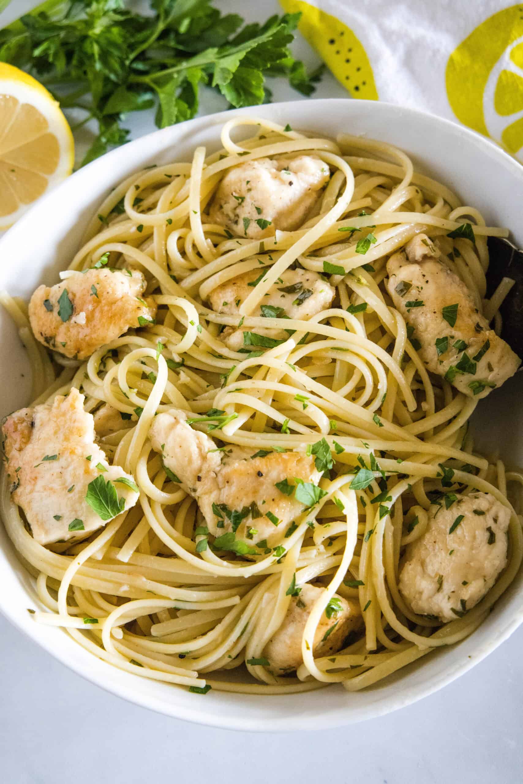 This chicken scampi recipe is a quick, easy chicken pasta with juicy chicken bites cooked in a buttery white wine sauce with garlic and lemon. Overhead view of chicken scampi with spaghetti in a white bowl.