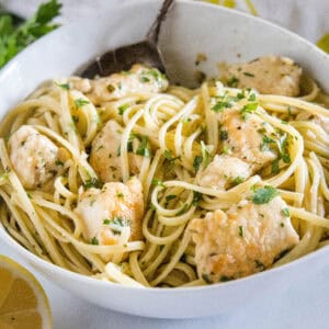 Chicken scampi with spaghetti in a white bowl.