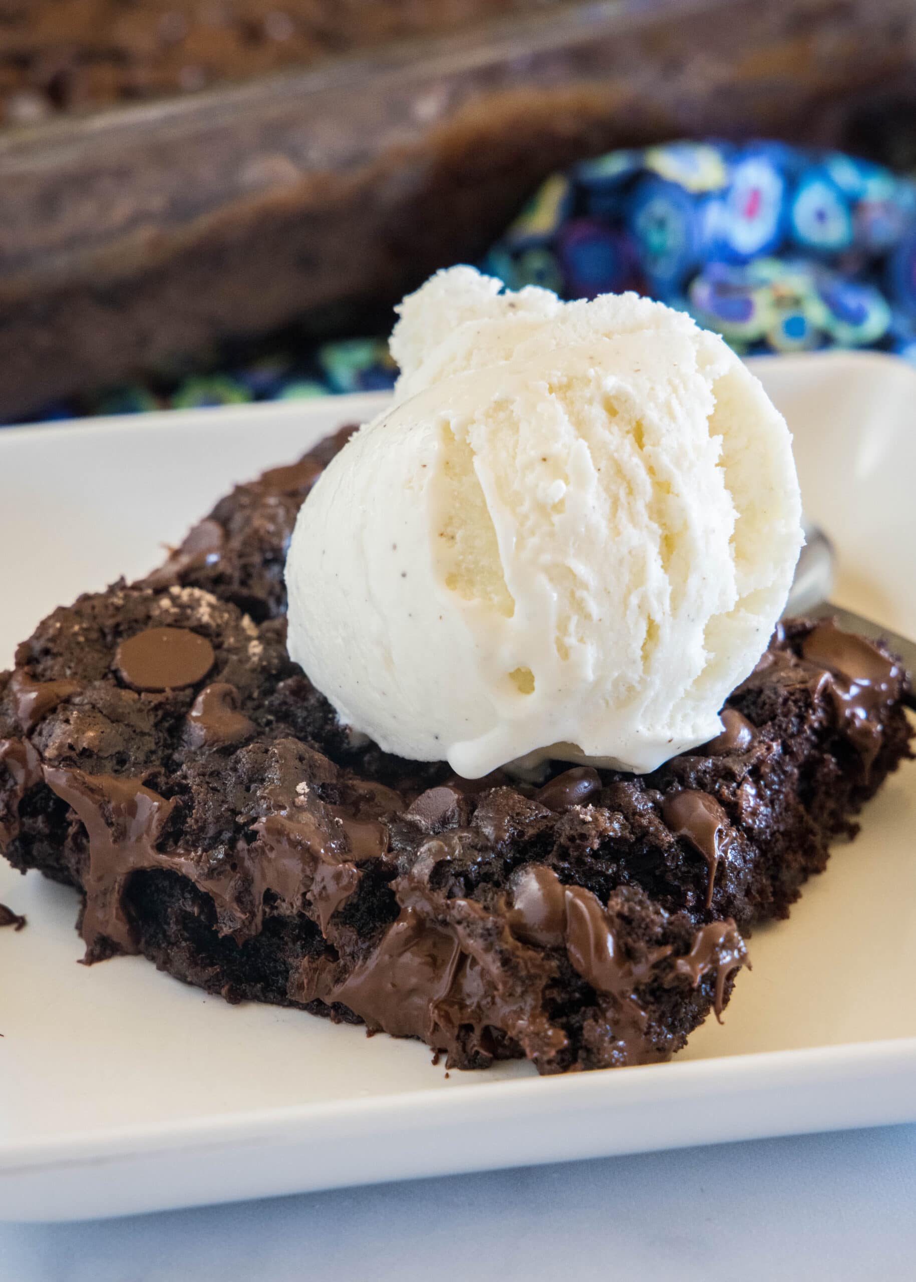 This 5-ingredient chocolate dump cake is the easiest chocolate dessert ever, and the most indulgent, with gooey chocolate in every bite! A slice of chocolate dump cake topped with a scoop of vanilla ice cream on a white plate.