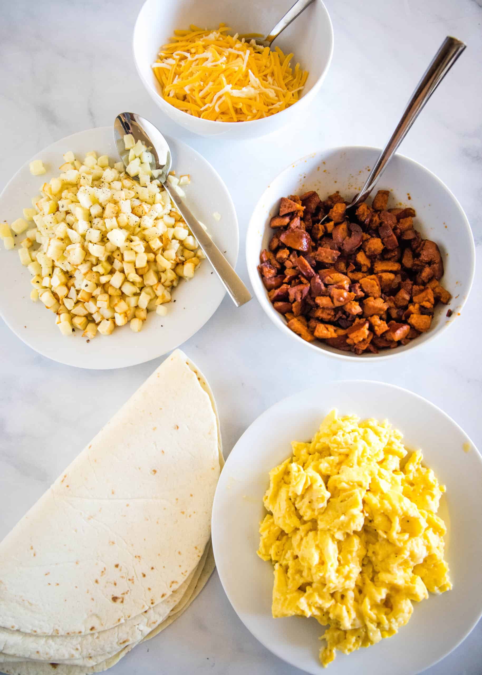 This chorizo breakfast burrito is a cheesy breakfast wrap loaded with crispy hash brown potatoes, spicy chorizo sausage, and fluffy eggs! Chorizo breakfast burrito ingredients.