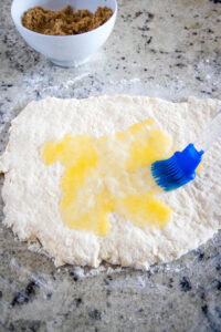 dough rolled out being brushed with butter