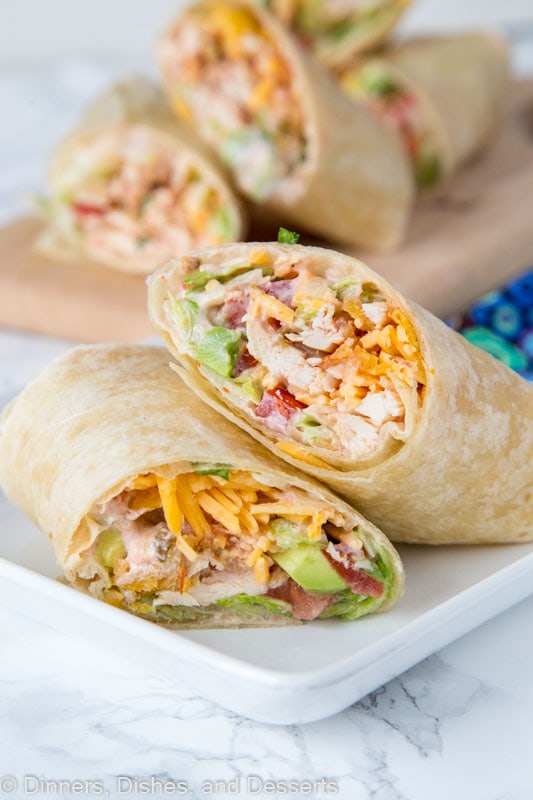These crunchy southwestern chicken wraps are an easy, healthy lunch that you can make in just 15 minutes. Plus they're filled with Fritos! A chicken wrap cut in half, diagonally, with one half leaning against the other, on a plate, with a cutting board full of wraps in the background