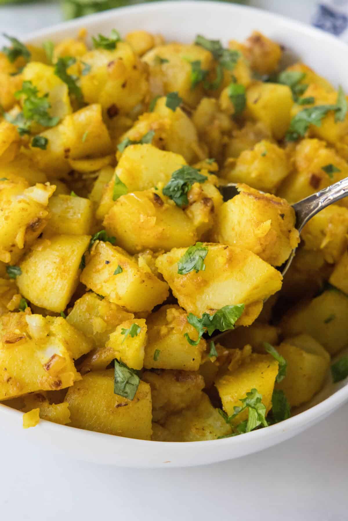 Curried Potatoes with Chickpeas scooping potatoes out of serving dish