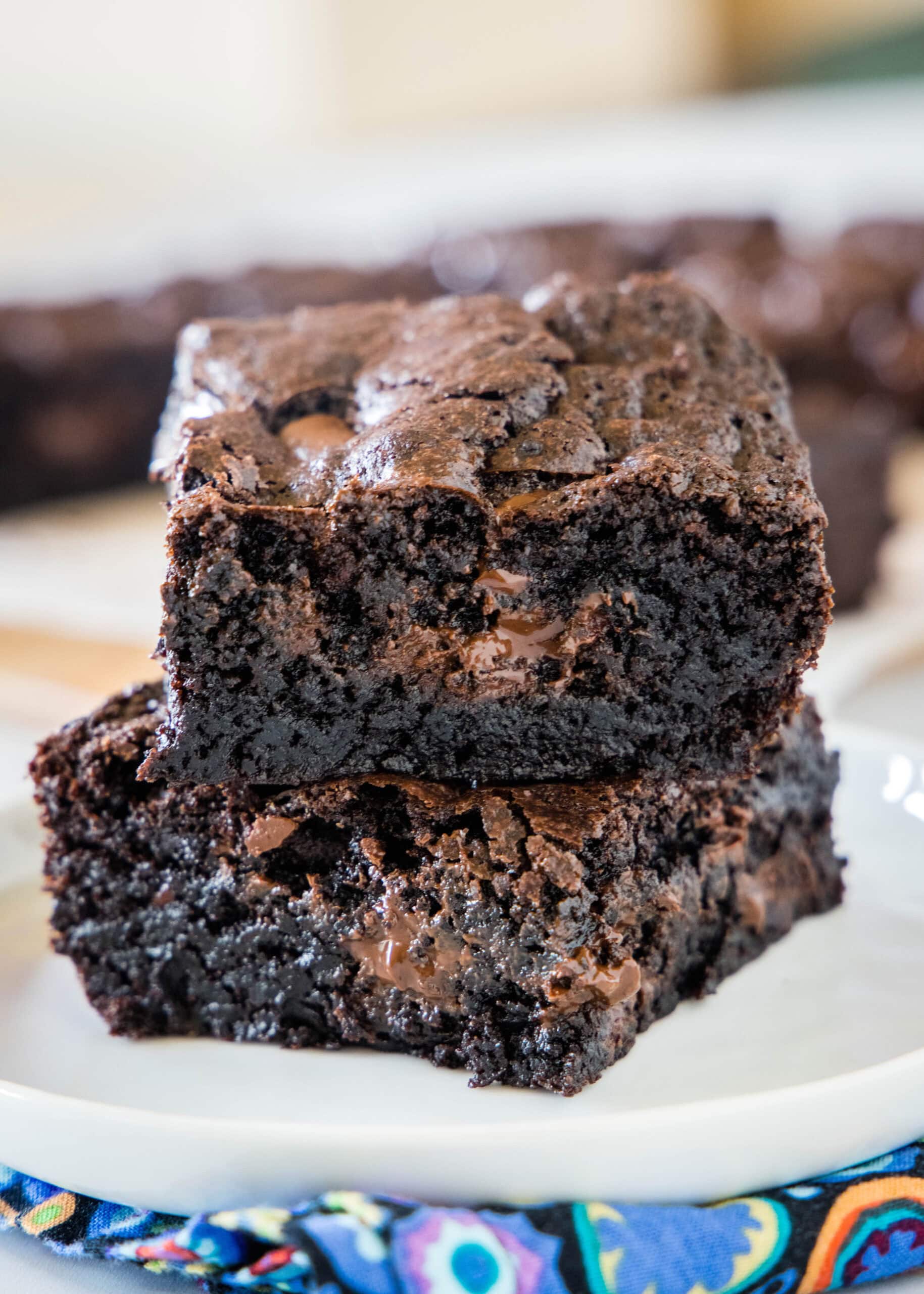 Two double chocolate brownies stacked on a plate.