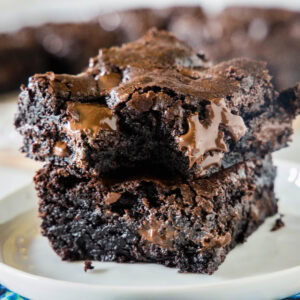 Two double chocolate brownies stacked on a plate with a bite missing from the top brownie.