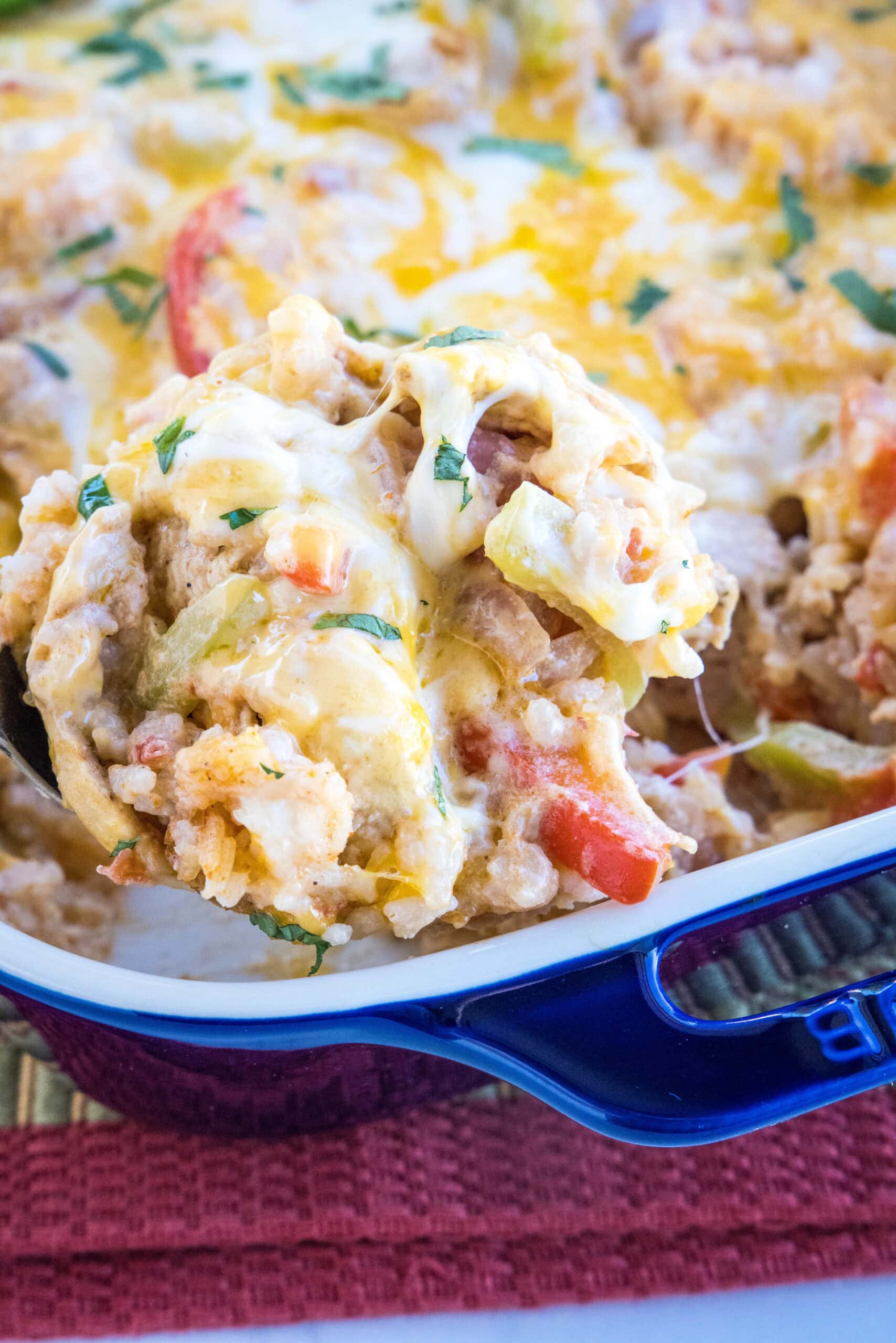 This chicken fajita casserole is an easy dinner packed with juicy chicken and rice, with sweet bell peppers, fajita seasoning, and cheese! A serving of chicken fajita casserole being scooped from a baking dish.