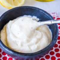 close up spooning garlic aioli from a small bowl
