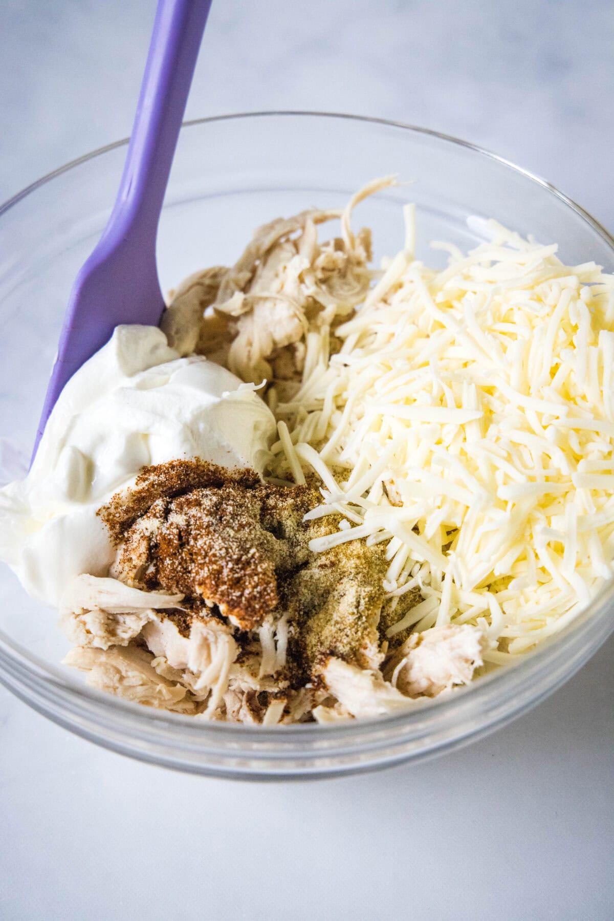 mixing together green chile chicken enchilada filling ingredients in a bowl