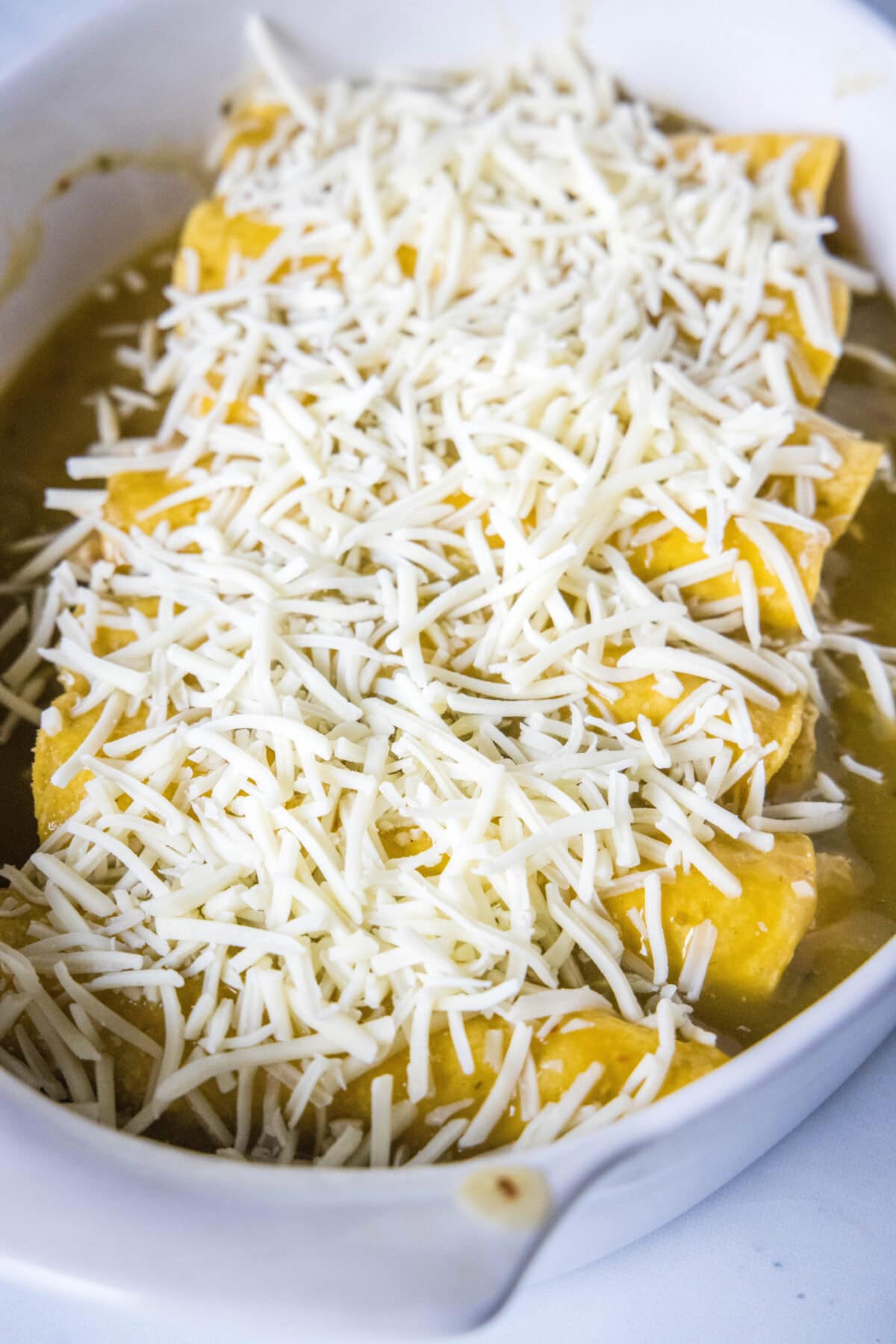 enchiladas topped with cheese ready to be baked