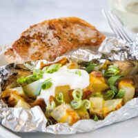 grilled potato pack on a plate with a pork chop