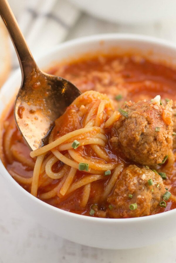 spaghetti and meatball soup in a bowl with a spoon