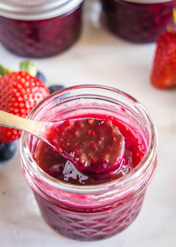 spooning out berry jam from a jar