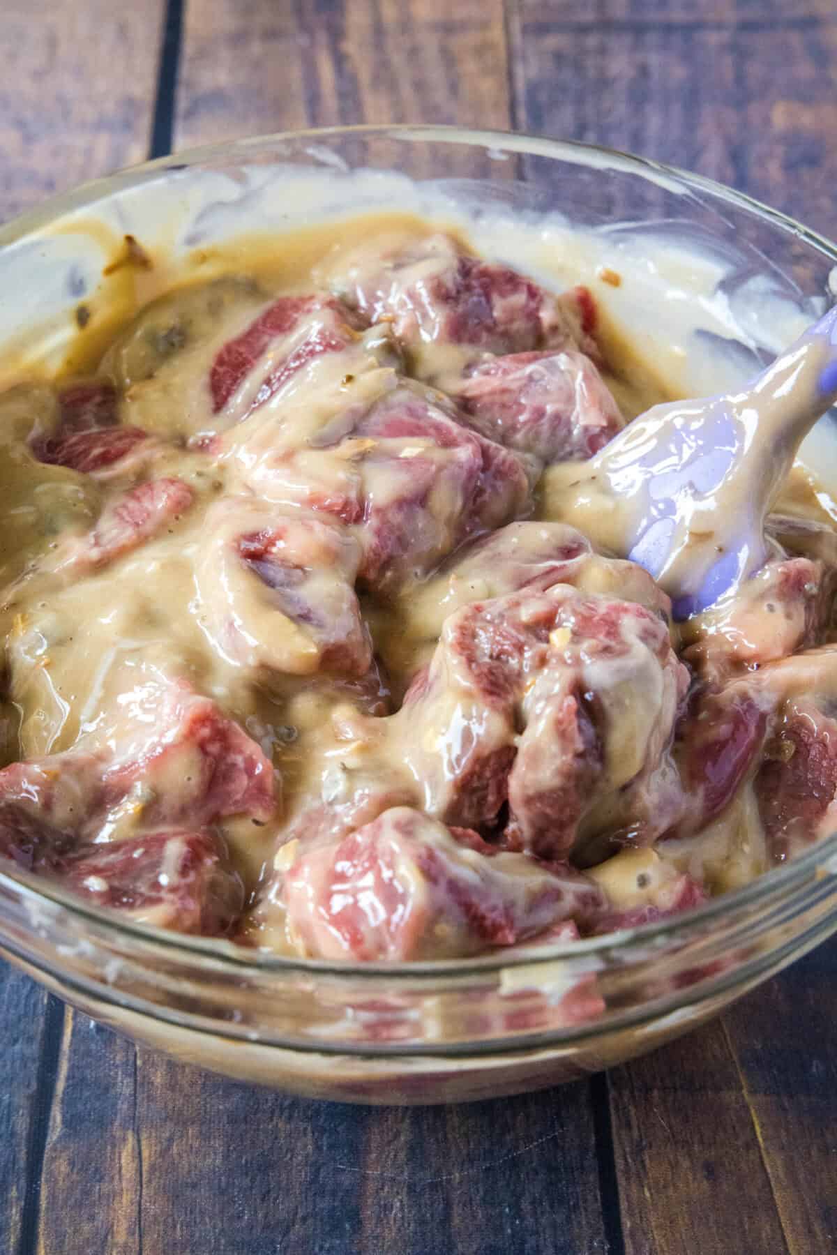beef tips coated in sauce in mixing bowl