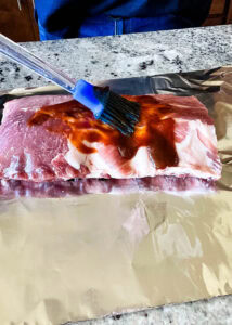 brushing sauce on raw baby back ribs