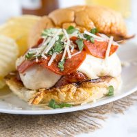 pepperoni pizza burger on a plate with potato chips