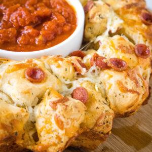 Pizza monkey bread with a bowl of pizza sauce in the middle hole.