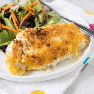 Baked ranch chicken served with a side of salad on a white plate.