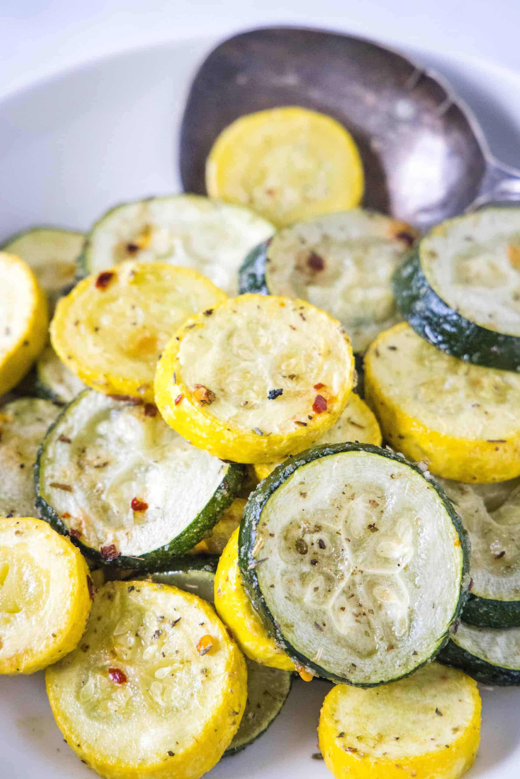 Make perfectly tender-crisp roasted zucchini and squash in the oven. It's an easy vegetable side dish that's ready in 20 minutes! Roasted zucchini and squash in a bowl with a serving spoon.