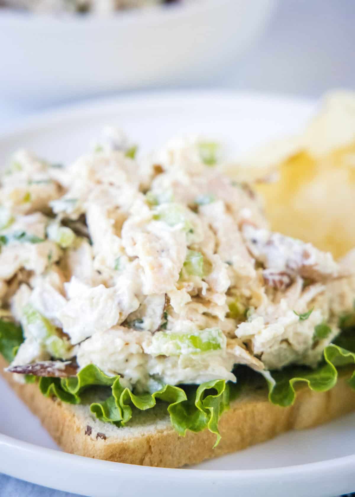 rotisserie chicken salad on a slice of bread with lettuce on a plate