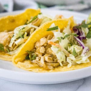 Two salsa verde chicken tacos on a white plate.
