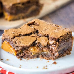 Close up of a salted caramel brownie with a bite missing on a white plate.