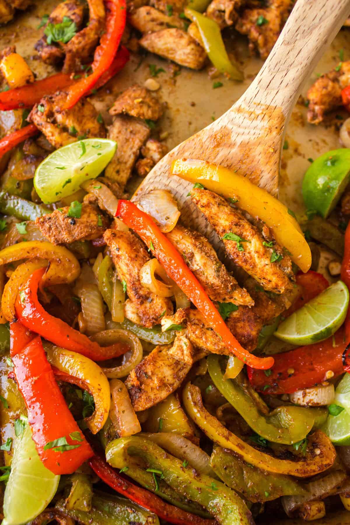 scooping chicken fajitas off a sheet pan