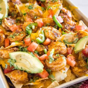 Shrimp nachos on a sheet pan garnished with avocado slices.