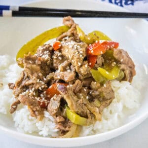 cropped close up pepper steak over rice on a white plate