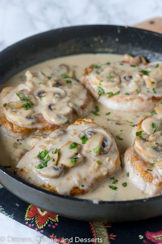 Smothered pork chops are a comforting one-pan recipe with juicy, pan-seared chops drenched in a creamy mushroom gravy. Quick and delicious! Smothered pork chops with mushroom gravy in a skillet.