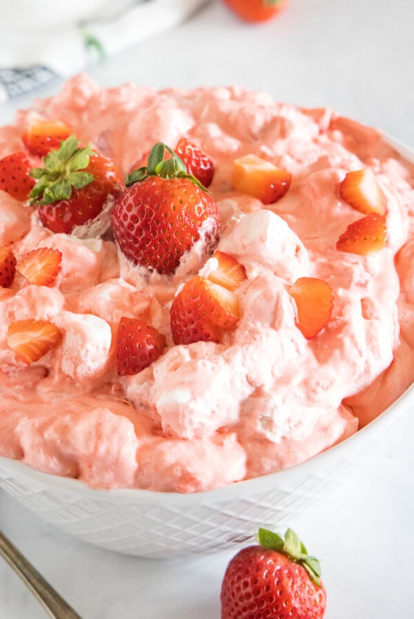 Strawberry fluff topped with chopped strawberries in a white bowl.