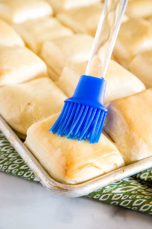 baked rolls being brushed with butter