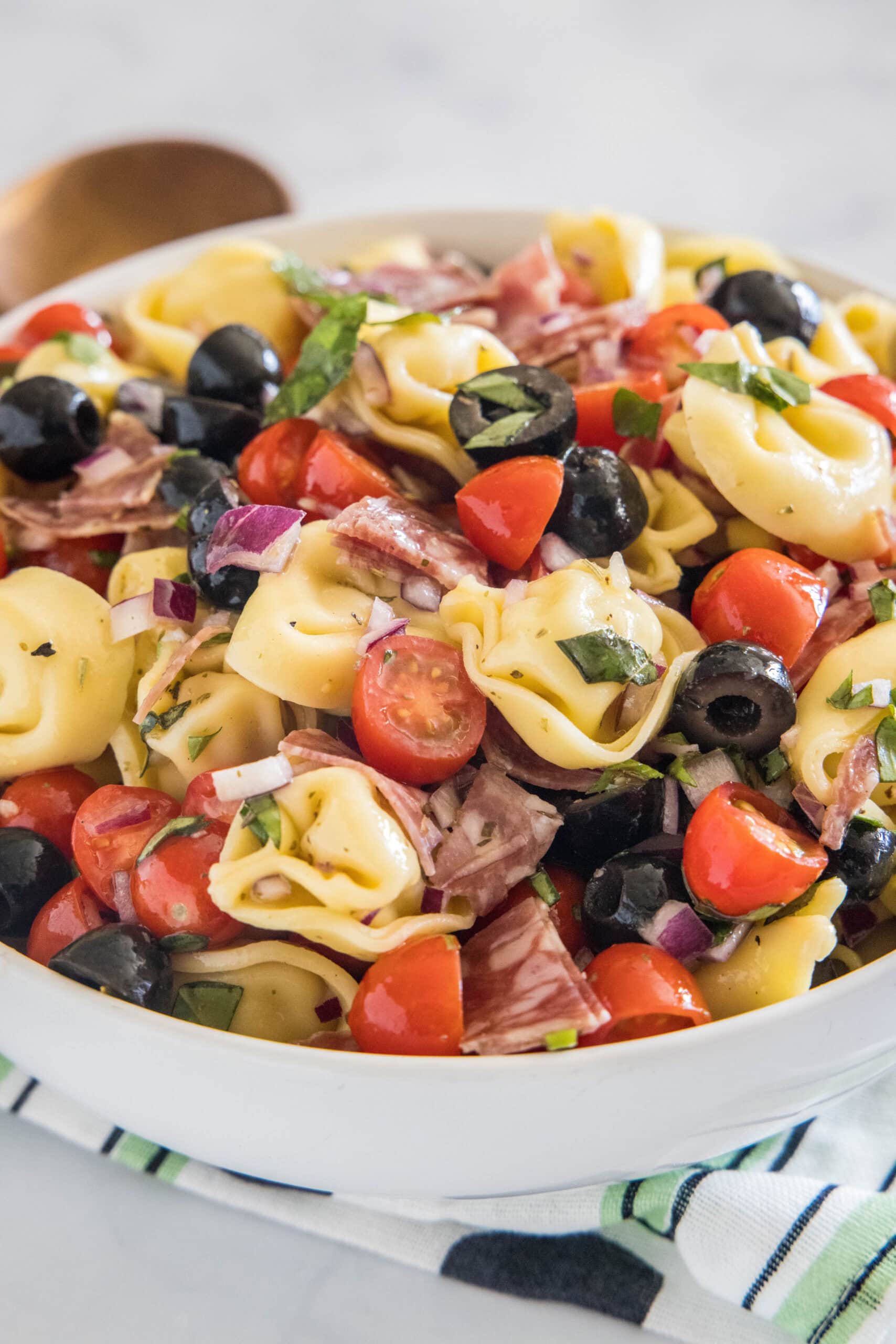 This tortellini pasta salad is an easy summer side or light meal packed full of Italian-inspired flavors, tossed in a zesty homemade dressing! Tortellini pasta salad in a white bowl.
