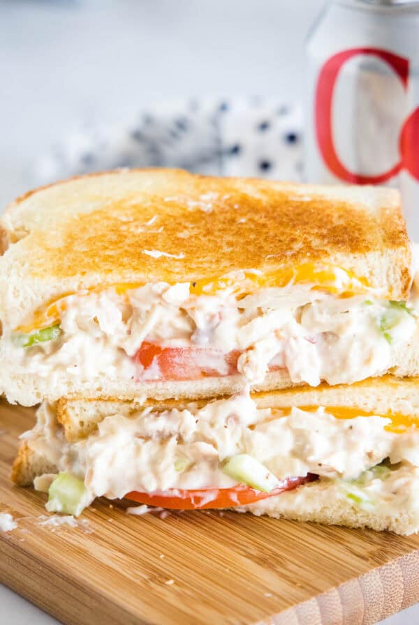 Two halves of a tuna melt stacked on top of one another on a wooden platter.